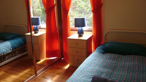 1 dormitorio con cortinas rojas, 1 cama y espejo en Accommodation Sydney North - Forestville 4 bedroom 2 bathroom house, en Forestville
