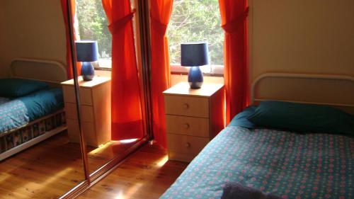 um quarto com cortinas vermelhas, uma cama e um espelho em Accommodation Sydney North - Forestville 4 bedroom 2 bathroom house em Forestville