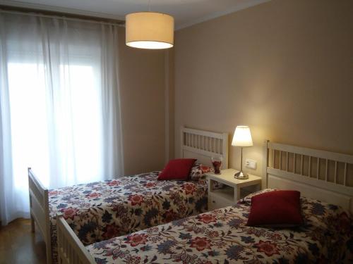 a bedroom with two beds and a lamp and a window at El Collado 17 in Soria