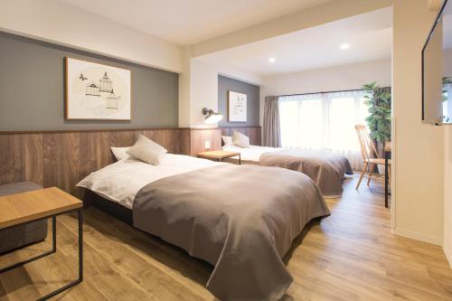 a hotel room with two beds and a table at Hotel Replace Namba Osaka in Osaka