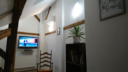 a hallway with a tv and a chair in a room at Kisfaludy Sándor Apartman in Győr
