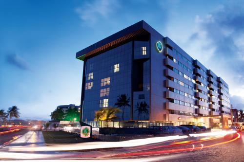 a building on a street with cars speeding past it at Ritz Suites Home Service in Maceió