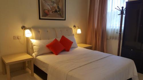 Kurau Inn Farmstay في Kuala Kurau: غرفة نوم بسرير أبيض ومخدتين حمراء