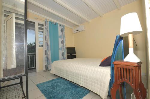 a bedroom with a bed with a lamp and a window at LOUE F3 VUE SUR MER DANS PROPRIETE PRIVEE in Sainte-Anne