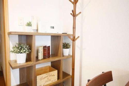 a wooden book shelf with plants and books at Minoshima Apartment 406 in Fukuoka