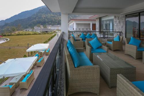 a balcony with wicker chairs and blue pillows at Mountain Glory Forest Resort in Pokhara