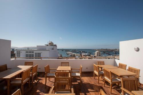 a patio with wooden tables and chairs on a roof at Hotel Riviera Inka Paracas in Paracas