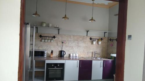 a kitchen with purple and white cabinets and appliances at Trendy apartments in Entebbe