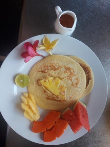 a plate of food with fruit and a cup of coffee at Trawangan Oasis in Gili Trawangan