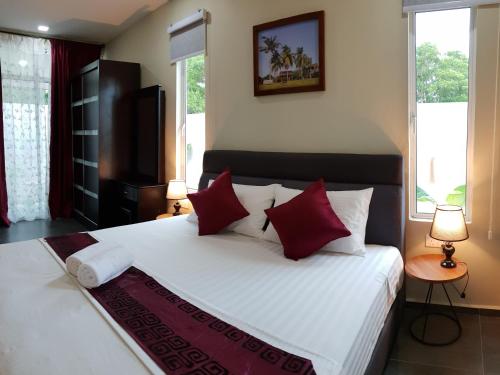 una camera da letto con un grande letto bianco con cuscini rossi di Chenang Inn a Pantai Cenang