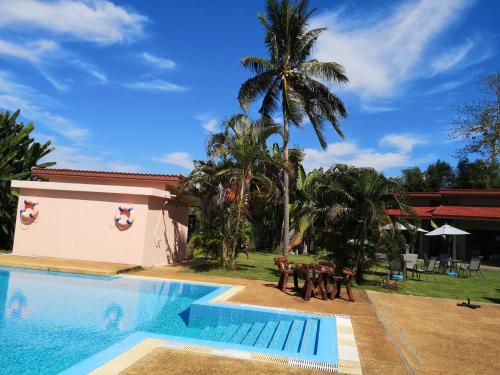 a swimming pool with a table and a palm tree at Sleep Soundly By The Sea in Trat