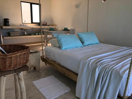 a bedroom with a bed with blue pillows and a sink at LunArena Barefoot Comfort in El Cuyo