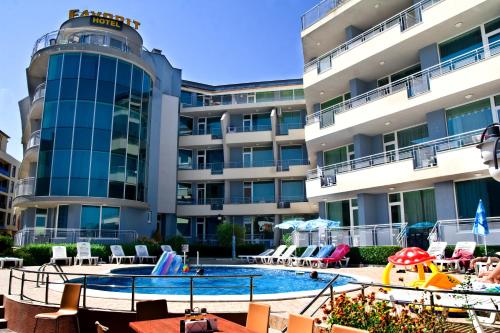 Un hotel con piscina y sillas y un edificio. en Favorit Aparthotel, en Sunny Beach