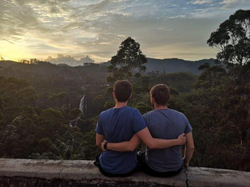 two men sitting on a ledge looking out over a valley at Princess of Dickoya Homestay in Hatton