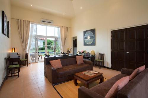 a living room with two couches and a table at Villa Bougainvillea in Hua Hin