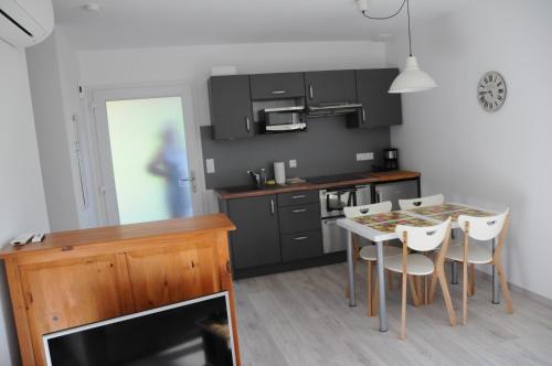 une cuisine avec une table et des chaises et une cuisine avec des armoires noires dans l'établissement Gites au jardin, à Morsbronn-les-Bains