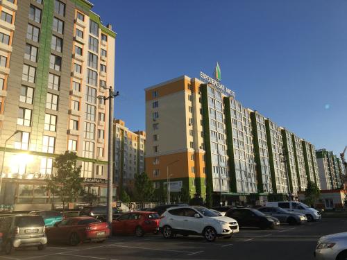 a large building with cars parked in a parking lot at Апартаменты в 3км аэропорта Киев in Vyshneve