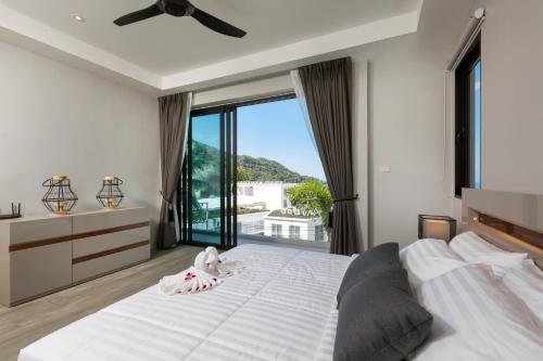 a bedroom with a large white bed and a large window at Twin Villas Seaview Kata in Kata Beach