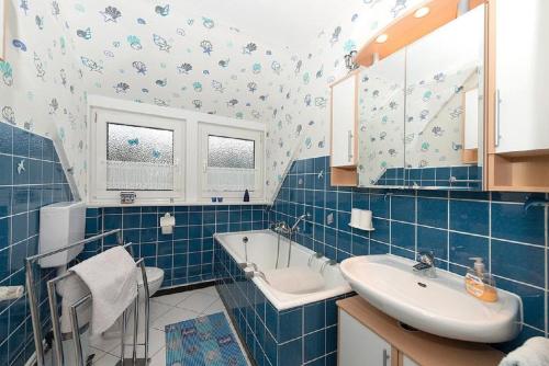 Ferienwohnung Poppe في Loxstedt: حمام من البلاط الأزرق مع حوض استحمام وحوض استحمام