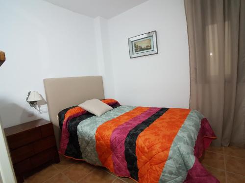 een slaapkamer met een bed met een kleurrijke deken bij Hostal Mesón La Era in Ríogordo