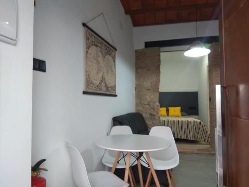 - une table et des chaises blanches dans une chambre avec un lit dans l'établissement Caleros 8 Estudio - Apartamentos de la Parte Antigua de Cáceres, à Cáceres