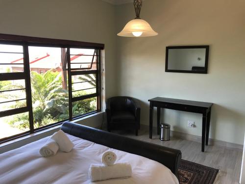 a bedroom with a bed and a chair and a mirror at Sandy Bottoms in Jeffreys Bay