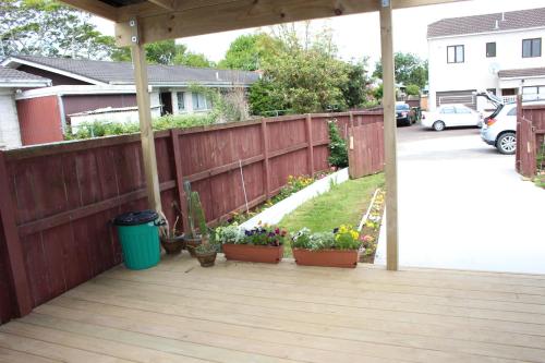 a patio with pots of flowers and a fence at Mini Homestay in Auckland