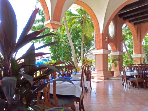 a restaurant with tables and chairs and palm trees at Canadian Resort Huatulco in Santa Cruz Huatulco