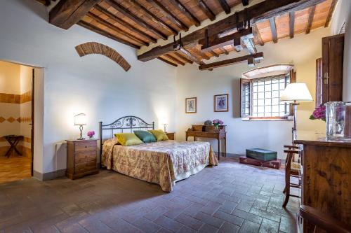 um quarto com uma cama, uma mesa e uma janela em Villa S.Andrea em San Casciano in Val di Pesa