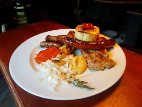 a white plate with sausage and other food on a table at Guest House Kraljev Hrib in Kamniška Bistrica