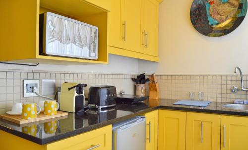 a kitchen with yellow cabinets and a black counter top at 1AA Wilhelmina Luxury Suites in Franschhoek