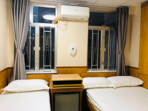 two beds in a room with a window at Good Fortune Inn in Hong Kong