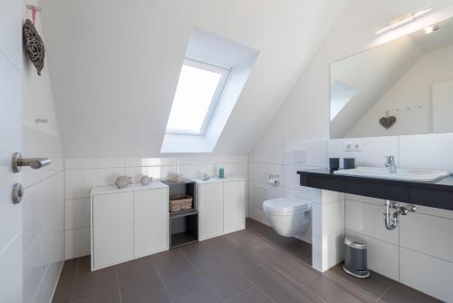 a white bathroom with a sink and a toilet at Haus Strandhafer in Börgerende-Rethwisch