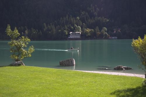 a boat on a lake with a house in the water at Agriturismo Ai Castioni in Molveno