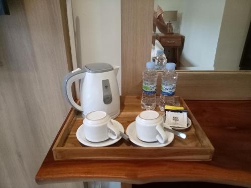 a tray with a coffee maker and cups and water bottles at Guest House Reisya in Nusa Dua