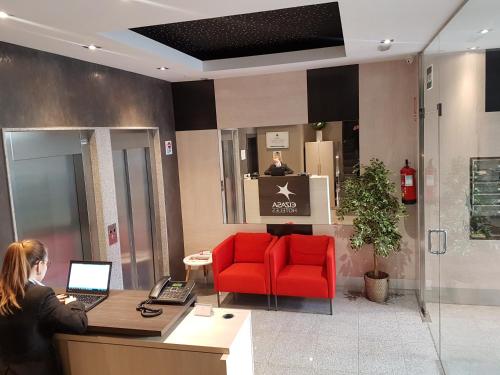 a woman sitting at a desk with a laptop in a lobby at Apartamentos Real Lleida in Lleida