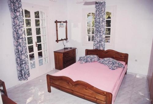 a bedroom with a bed and a dresser and two windows at Villa Errieta in Athéras