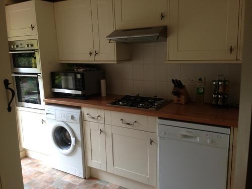 a kitchen with a washing machine and a microwave at Brook Cottage in Chipping Campden