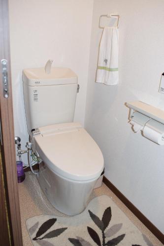 aseo blanco en un baño con alfombra en Share House Amigos, en Onomichi