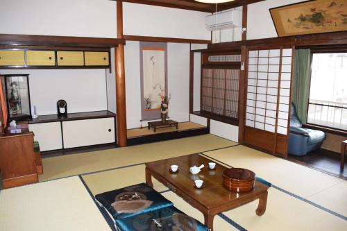 a living room with a table and some windows at Share House Amigos in Onomichi