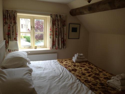 a bedroom with a white bed with a window at Brook Cottage in Chipping Campden