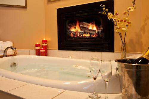 a bath tub with two wine glasses and a fireplace at Inn on The Creek in Jackson