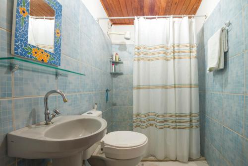 een badkamer met een wastafel, een toilet en een douchegordijn bij Pousada Casa de Nomades in Vale do Capao