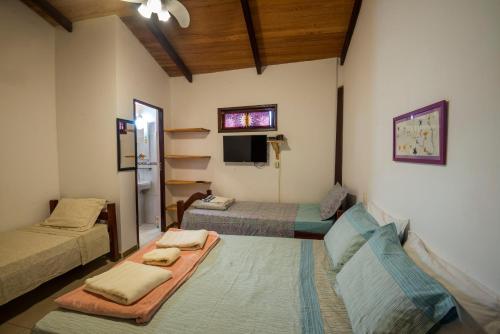 een woonkamer met 2 bedden en een televisie bij Pousada Casa de Nomades in Vale do Capao