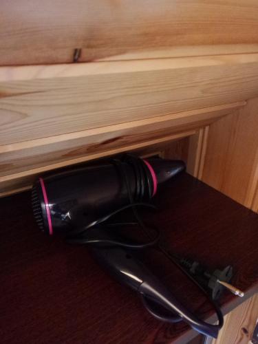 Ein schwarzer Haartrockner hängt an einer Holzschublade in der Unterkunft Relax House in Varkaliai