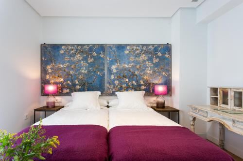 a bedroom with a large bed with a painting on the wall at Apartamentos RG Plaza de España in Seville