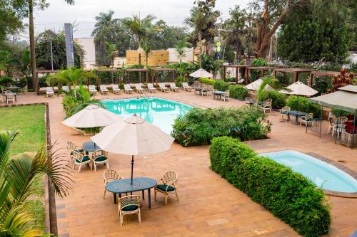 an outdoor pool with chairs and tables and umbrellas at Fairway Boutique Hotel - Kampala, Uganda in Kampala
