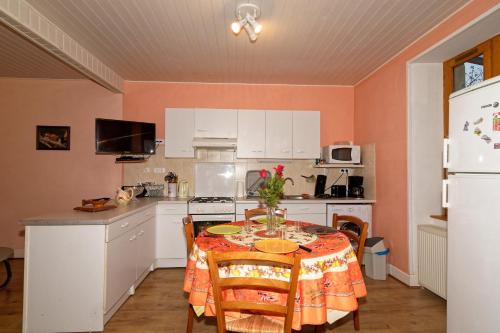 een keuken met een tafel en een keuken met witte kasten bij gite de Sauviat 25 chemin du grand Pacher le bourg de Sauviat 63120 in Sauviat