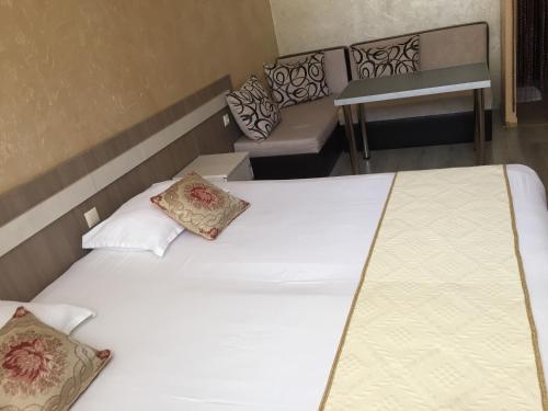 two twin beds in a room with a bench at Семеен Хотел Русалка in Svishtov