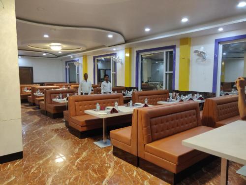 a restaurant with brown chairs and tables and two people at Bodhgaya Seven Inn Hotel n Restaurant in Bodh Gaya